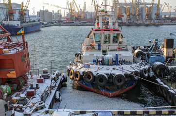 The tugboat is at the pier in the port. Wiew of the evening port in winter