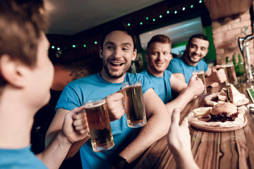 Soccer fans watching the game drinking beer and eating at sports bar.