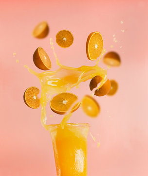 concept of healthy food, fresh juice, splashes and drops from orange slices fly out of the bottle, on a pink background