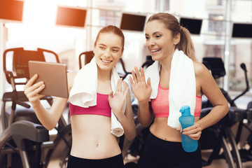 Mother and daughter using tablet at the gym. They look happy, fashionable and fit.