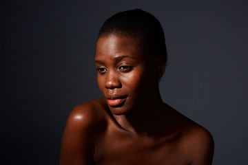 Close up attractive young african woman against gray background with naked shoulders