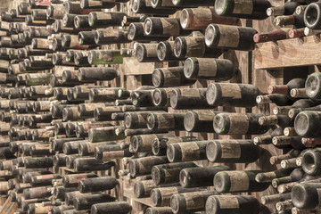 Many old wine bottles stacked on wooden racks