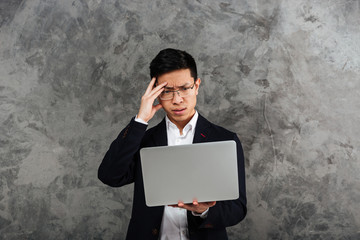 Portrait of a frustrated young asian man dressed in suit