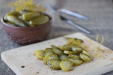 Sliced marinated cucumber on a wooden board.
