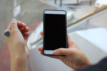 young woman listening wireless music with headphones from a smart phone
