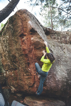 Rock climber woman climbing overhanging limestone boulder in Albarracin