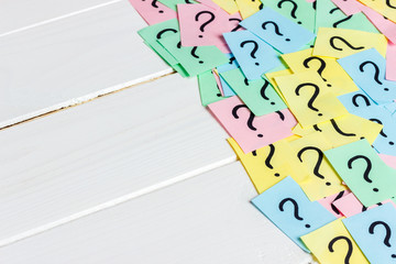 Just a lot of question marks on colored papers on wood background