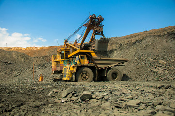 Excavator in the quarry loads the dumper with iron ore