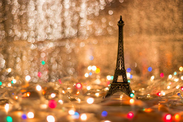 The Eiffel model is placed on a wooden table surrounded by light. Blurry background.