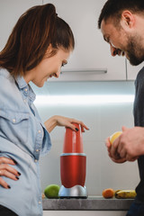 Couple laughing while blending smoothie in the kitchen