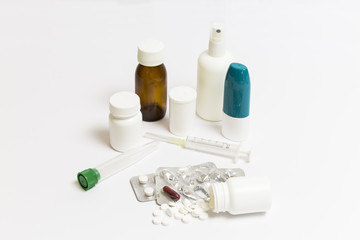 group of pills, medicine cans, spray, syrups and syringes on a white background
