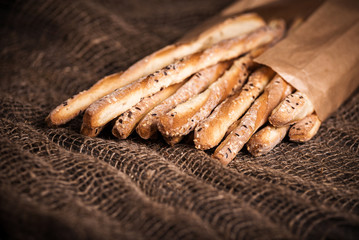 Delicious breadsticks grissini. Italian appetizers. Wooden dark background and burlap