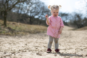 Dirty child crying in the sand