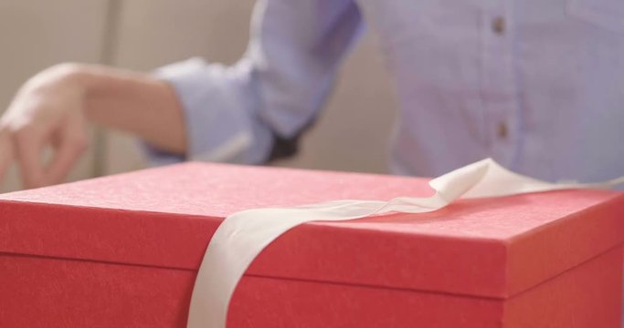 Beautiful blonde girl receives a present from her boyfriend and she opens it. concept of holidays and new year. the girl is happy and smiles with christmas gift in hand.