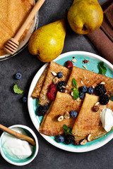 Homemade pancakes with berries and cream sauce on a black background.