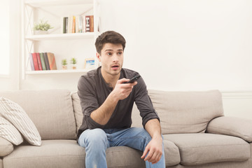 Obraz premium Młody mężczyzna ogląda telewizję za pomocą pilota