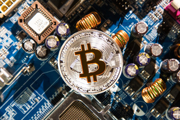 Silver coin with a gold bit of bitcoin on a background of microcircuits and computer spare parts