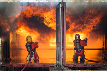 Fototapeta premium Firefighters training, Team practice to fighting with fire in emergency situation..Spray water to the flame in closed location
