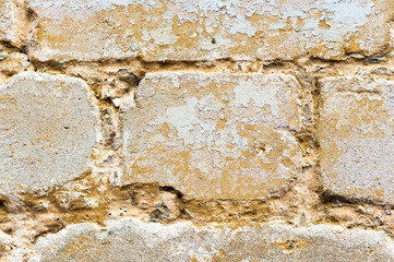 Close-up Textured background of a multi-colored brick painted in yellow. A sizzling yellow paint on an old broken brick. Grunge style