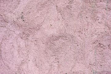 Textured background The outer surface of the wall of a residential house is plastered. Rough texture fancy patterns of ointment on external plastering work of pink color