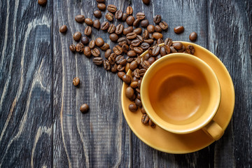A coffee cup with coffee beans on an old wooden table. Fried coffee beans on a wooden background. Viewing from above.