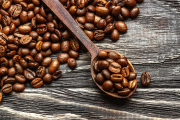 A coffee cup with coffee beans on an old wooden table. Fried coffee beans on a wooden background. Viewing from above.