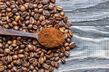 A coffee cup with coffee beans on an old wooden table. Fried coffee beans on a wooden background. Viewing from above.