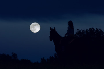 Couple: girl rider and horse are looking at the big full moon at night and dreaming. Fantasy...