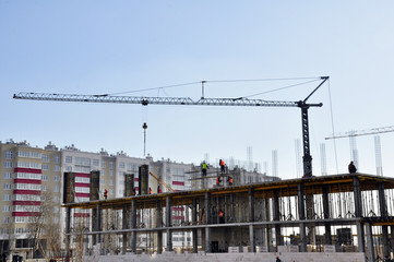 close-up construction of a multi-storey house of blocks and bricks. Construction equipment and workers carry out installation of the building and conduct preparatory work.