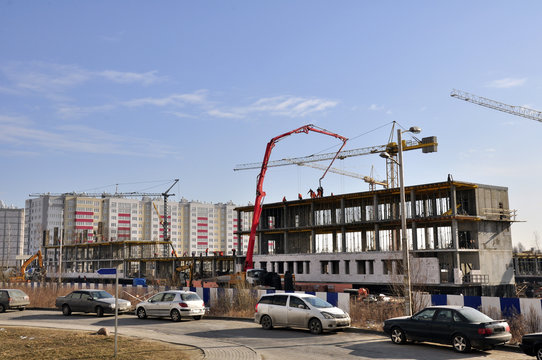 close-up construction of a multi-storey house of blocks and bricks. Construction equipment and workers carry out installation of the building and conduct preparatory work.