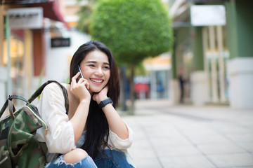 Fototapeta premium Asia woman talking with smart phone in the street in a sunny summer day