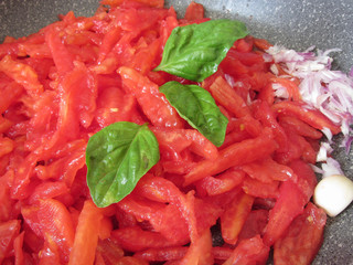 Tomato sauce for pasta cooking in the pan, italian recipe . The ingredients are fresh tomatoes, onions, olive oil, basil, garlic and salt