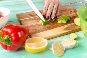 women's hand cut with a ceramic knife cucumber on a cutting Board