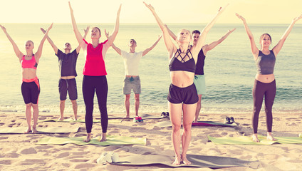Obraz premium People practicing yoga on beach