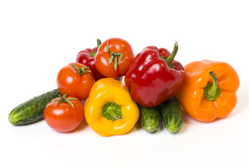 Red yellow and orange peppers with tomatoes on a white background. Cucumbers with colorful peppers in composition on a white background