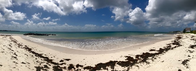 Panorama of an idyllic and beautiful beach in Barbados (Caribbean island): Nobody, white sand, turquoise water, waves and white clouds