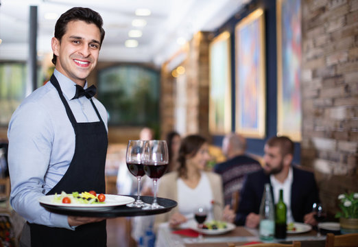 Professional waiter holding serving tray for restaurant guests