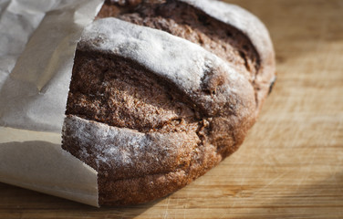 Fresh rye bread in a paper bag on a wooden board