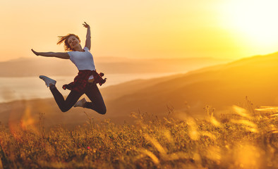 Fototapeta Happy woman jumping and enjoying life  at sunset in mountains. obraz