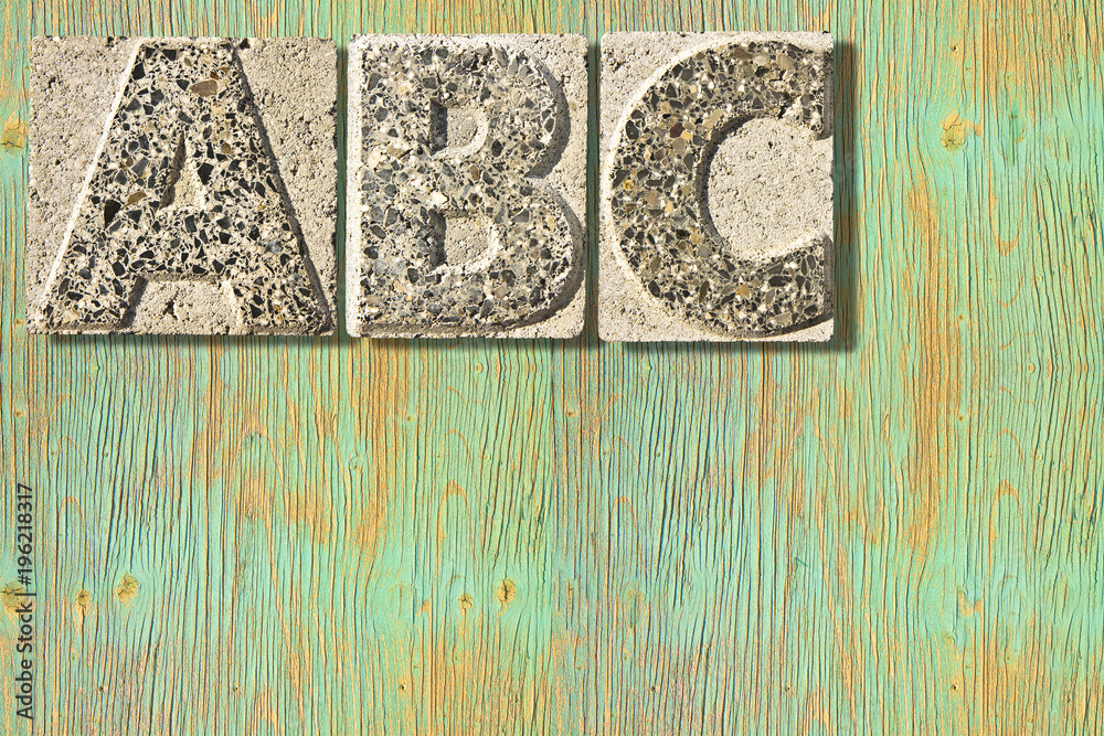 Fototapete Letter A-B-C carved in a concrete block over a wooden background - concept image with copy space