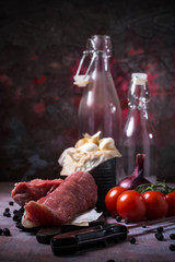 Whole pork tenderloin meat on vintage board with red tomatoes and garlic