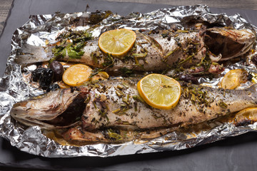 two seabass fish baked in the oven or on the grill, on food foil