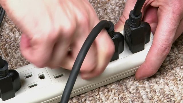 Multiple cables are plugged into a power strip.  This protects the electronics from surges.
