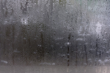 Moisture on the glass, formed in raindrops.