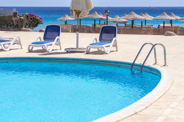 pool with blue water outside and red sea in a sunny day