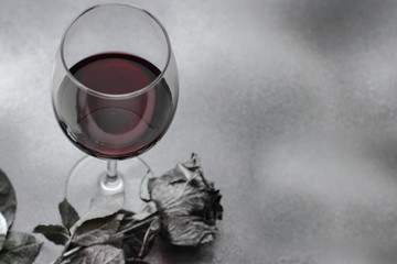 red wine in glass with silver rose on silver background flat lay, place for text