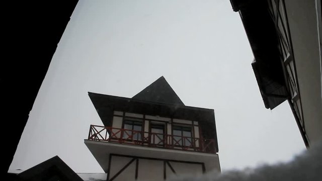The winter sky and snow falling on the background of the roof of a vintage house. Snow and vintage. Back background for the inscriptions and text on the background of the roof of the house and the bli