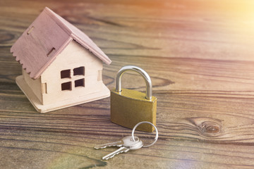 lock with keys and a house on a background of natural wood texture. Security, security, alarm....