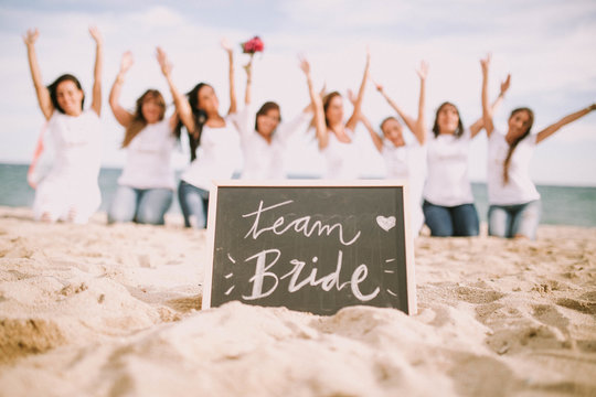 Women posing at blackboard on beach