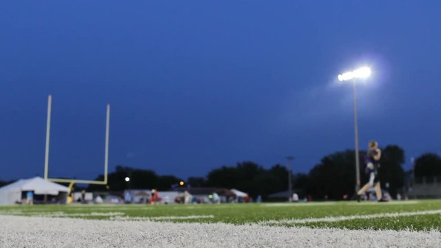 Football field with bright lights as smoke goes by them.
